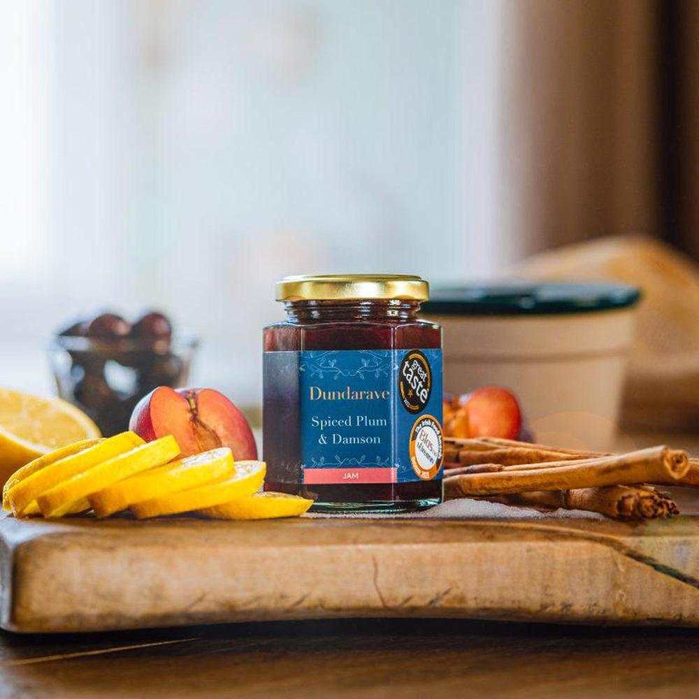 Dundarave Estate spiced plum and damson jam jar with fresh fruit and cinnamon sticks on wooden board