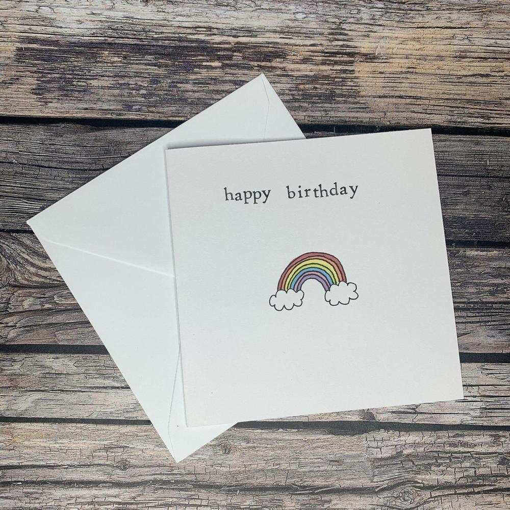 Hand made greeting card with happy birthday text and rainbow illustration on wooden background