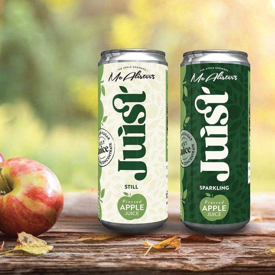 Cans of Mc Alisters Juist still and sparkling apple juice on wooden surface with fresh apple