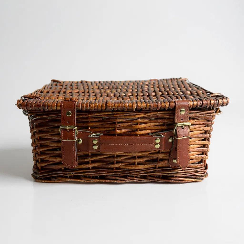 Medium wicker hamper with leather straps and lid, ideal for holding up to 12 items.