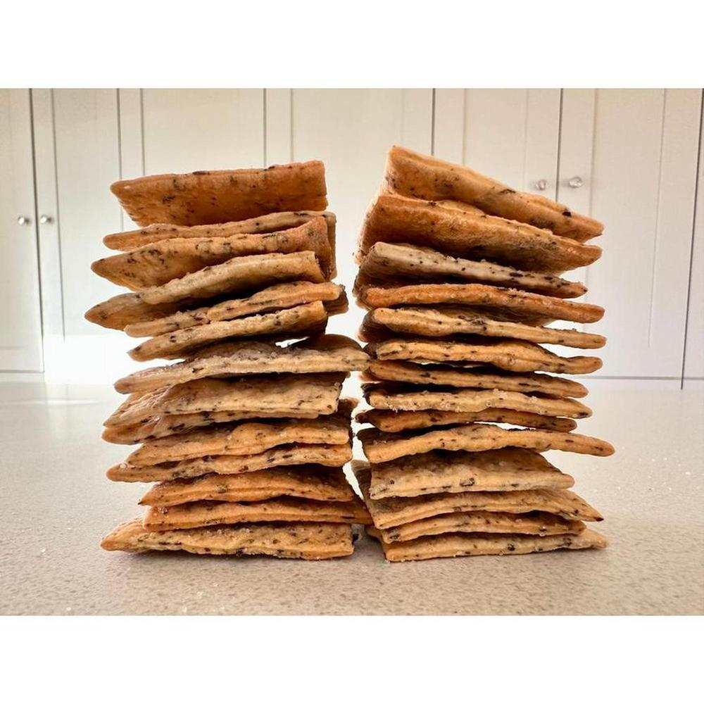 Two stacks of OMA crackers made with natural ingredients in various flavors on a kitchen counter